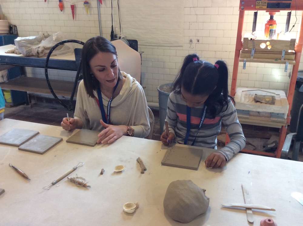 Two people make clay tiles.